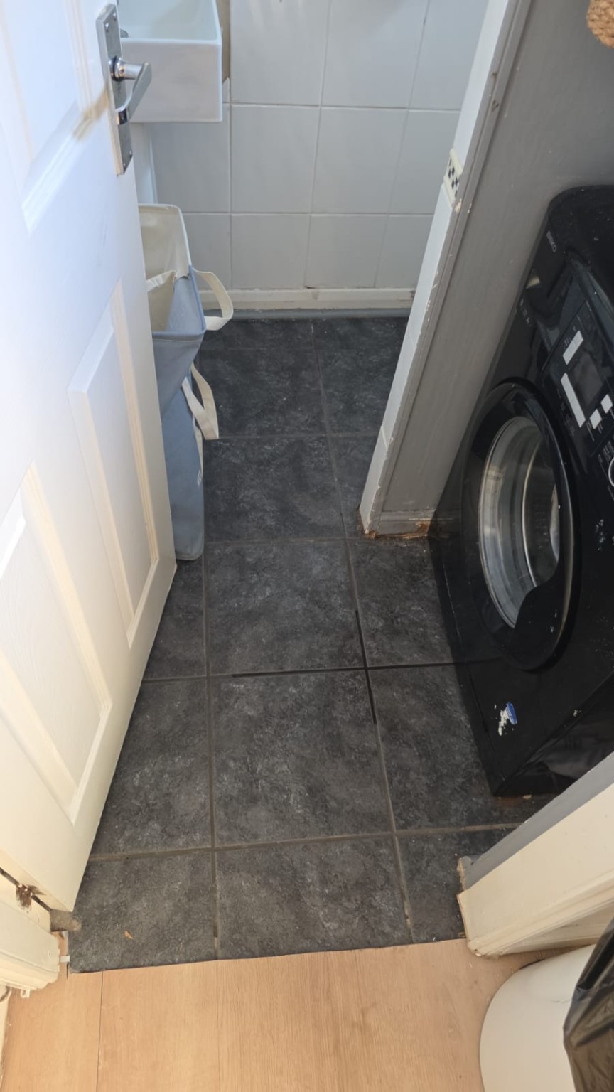 Utility and WC area before refurbishment with dark tiled floor